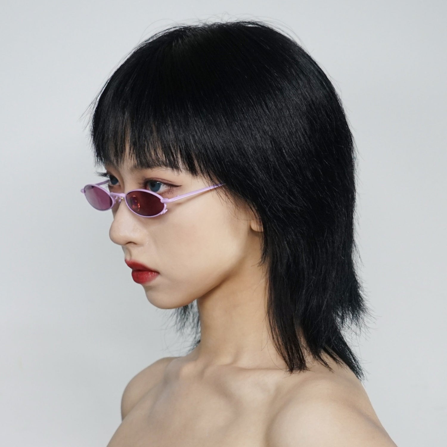 berry colour oval sunglasses in pink stainless steel frame with a tiny bug on the bottom of the right lens on model 45 angled 