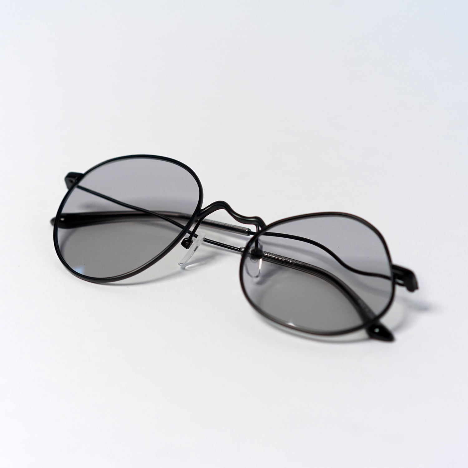 liquified round frames in matte black with grey polaroid lens temples folded up