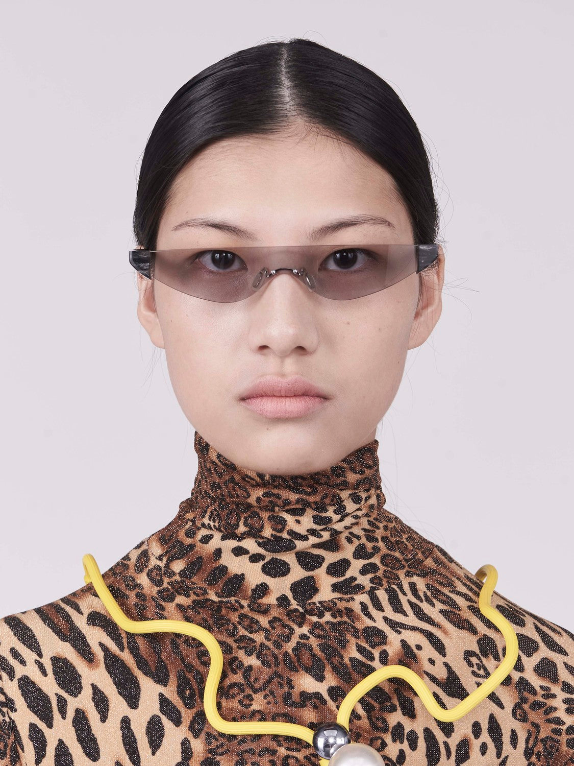 killer goggles style sunglasses with grey one-piece lens and marble hinges on model front